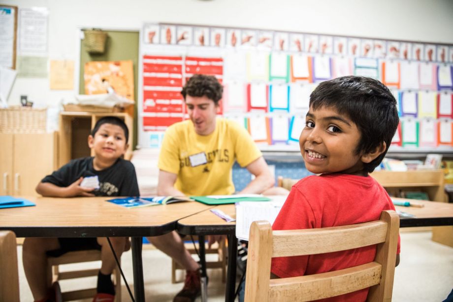Two students sitting with a tutor working at a table